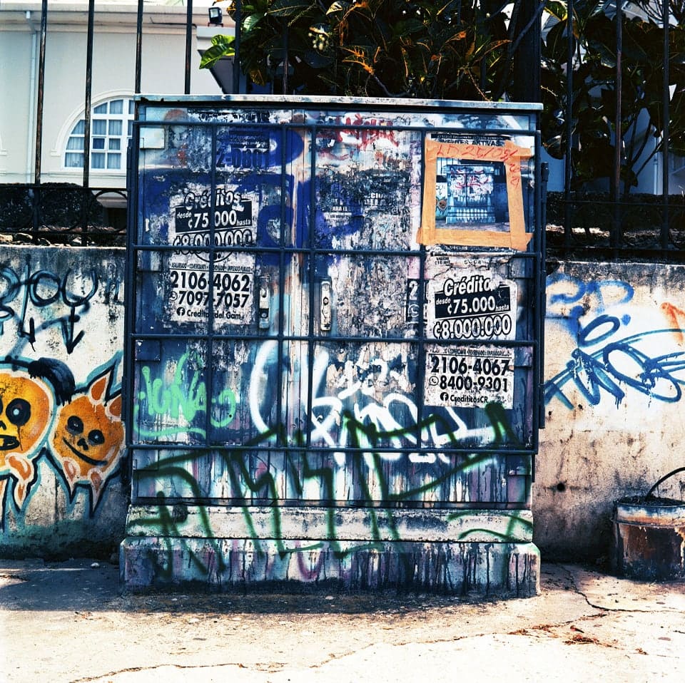 Caja de telecomunicaciones cubierta de graffiti y calcoman&iacute;as